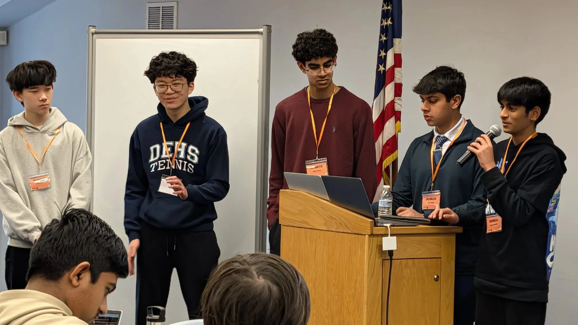 Five student organizers at the podium opening a Project Silicon event, badges on.