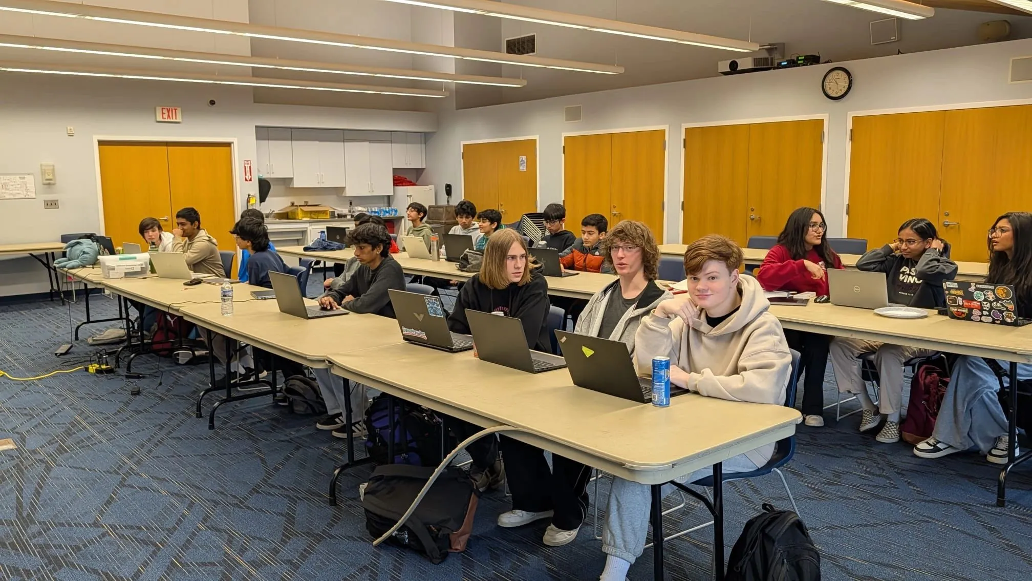 Students at long tables, laptops open, mid-hackathon.